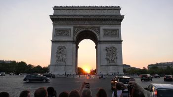 The sun sets in line with the Arc de Triomphe.